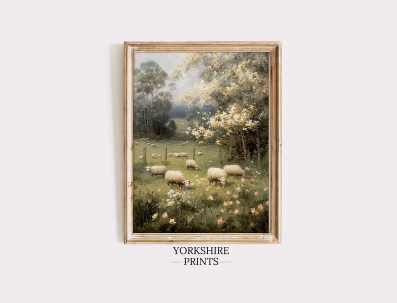 Op de afbeelding: Een ingelijst schilderij in vintage-stijl met schapen in een veld met bomen en bloemen. Het kunstwerk heeft een zacht kleurenpalet en is gevat in een rustieke houten lijst. De tekst "YORKSHIRE PRINTS" staat onderaan.