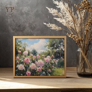 Puede incluir: Pintura de paisaje enmarcada que representa un jard&iacute;n de rosas rosas bajo un cielo azul con nubes blancas. La obra de arte est&aacute; en un marco de madera clara, sobre una superficie de madera. Hay hierbas ornamentales secas en un jarr&oacute;n de vidrio a la derecha.