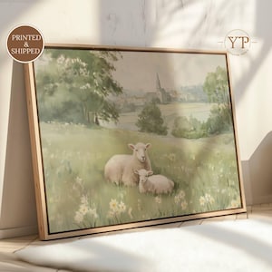 May include: A framed canvas print featuring a pastoral scene with two sheep in a field of flowers. The artwork has a soft, muted color palette with a light wooden frame. The print includes the text "Printed & Shipped".