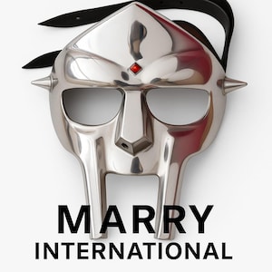 以下が含まれることがあります： 特徴的なデザインの研磨されたシルバーマスク。目立つ鼻、目の開口部、赤い宝石が特徴です。マスクには2つの鋭いスパイクと黒いストラップが付いています。「MARRY INTERNATIONAL」というテキストが黒で印刷されています。