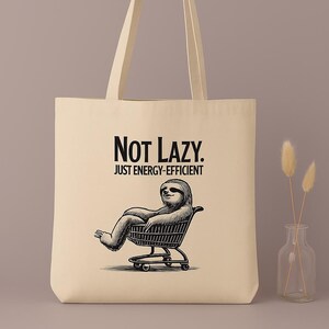 Tasche „Not Lazy. Just Energy-Efficient“ – Lustige Stofftasche mit chillendem Faultier im Einkaufswagen | Bio-Baumwolle, Beige, faul & cool