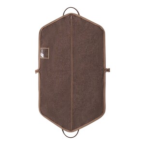 May include: A brown garment bag with a textured fabric. The bag has a full-length zipper, a small clear window, and a brown trim. It features two handles at the top and a loop at the bottom. The bag is designed to protect clothing.