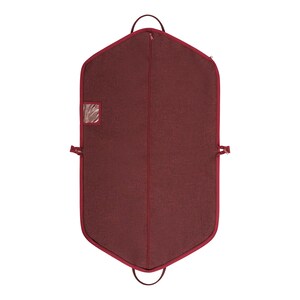 May include: A burgundy garment bag with a textured fabric. The bag has a full-length zipper, a clear window, and a handle at the top. It also has a handle at the bottom and two side straps.