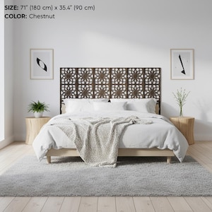 K&ouml;nnte beinhalten: Ein kastanienfarbenes Holz-Kopfteil mit floralem Muster, 180 cm breit und 90 cm hoch, ist der Mittelpunkt des Schlafzimmers. Das Bett ist mit wei&szlig;er Bettw&auml;sche und einem hellen Holzrahmen ausgestattet. Ein grauer Teppich bedeckt den Boden.