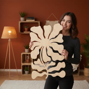 Peut inclure: Une grande &oelig;uvre d'art murale florale en bois clair avec un motif d&eacute;coup&eacute;. L'&oelig;uvre est tenue par une personne dans une pi&egrave;ce &agrave; la palette de couleurs chaudes, avec un lampadaire et des &eacute;tag&egrave;res en bois.