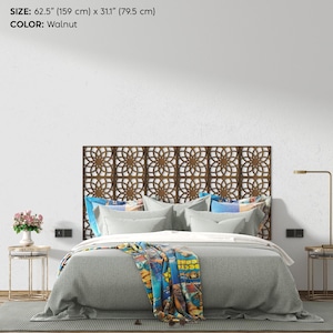 K&ouml;nnte beinhalten: Ein dekoratives Kopfteil in Walnussfarbe mit einem geometrischen Blumenmuster. Das Kopfteil ist 159 cm breit und 79,5 cm hoch. Das Bett ist mit grauer Bettw&auml;sche und bunten Kissen ausgestattet.