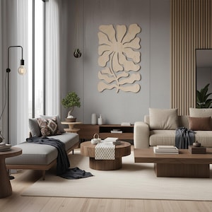 Peut inclure: Un salon moderne aux tons neutres. Une grande &oelig;uvre d'art murale en bois clair, repr&eacute;sentant un motif floral, est accroch&eacute;e &agrave; un mur gris. La pi&egrave;ce comprend une m&eacute;ridienne grise, un canap&eacute; beige et des tables basses en bois. Un lampadaire noir et une grande fen&ecirc;tre compl&egrave;tent la sc&egrave;ne.