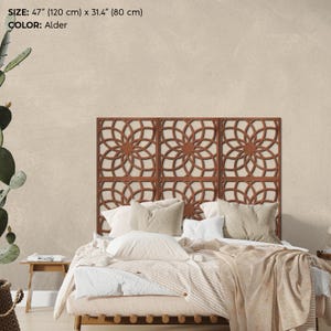 K&ouml;nnte beinhalten: Dekoratives Holz-Kopfteil mit geometrischem Blumenmuster, 120 cm breit und 80 cm hoch, in der Farbe Erle. Es befindet sich &uuml;ber einem Bett mit neutralfarbener Bettw&auml;sche. Ein dekoratives Element f&uuml;r das Schlafzimmer.