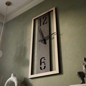 May include: A rectangular wall clock with a light wood frame and a dark wood centre. The clock face features cut-out numbers 12 and 6, with black clock hands. The clock is mounted on a green wall.