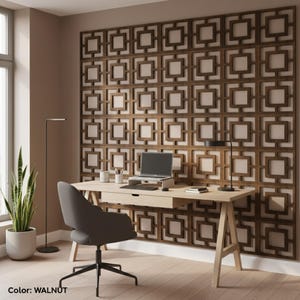 May include: A contemporary home office with a light wood desk, a grey office chair, and a laptop. The background features a walnut-coloured wall panel with a geometric square pattern. A floor lamp and a potted plant complete the decor.
