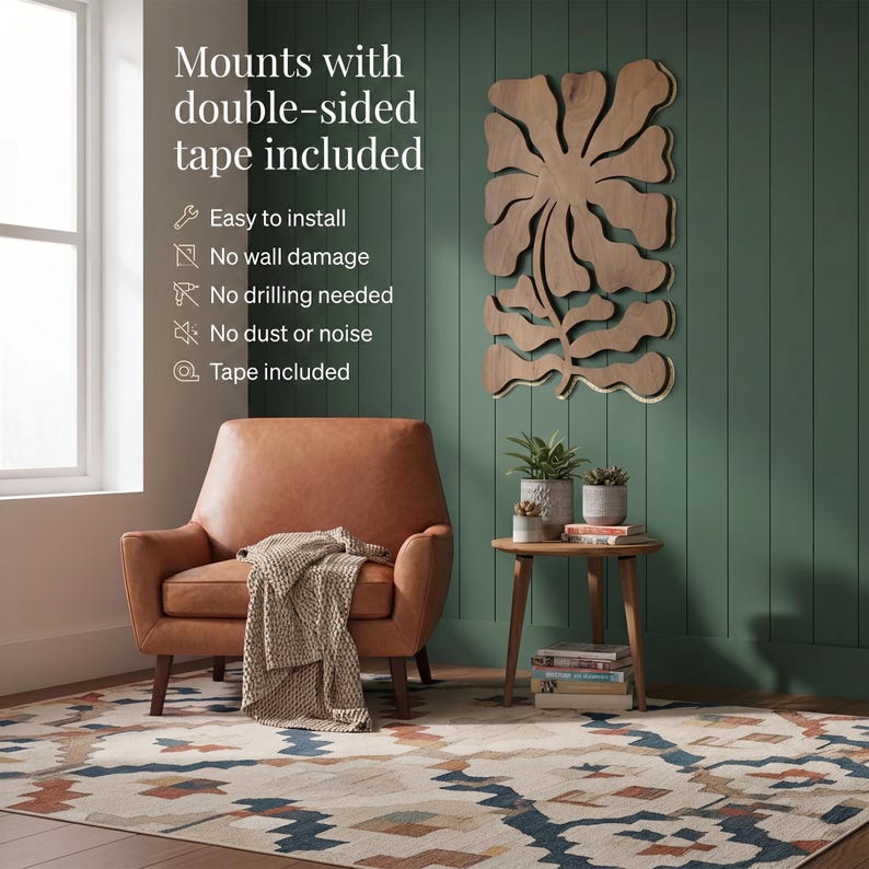 Peut inclure: Un salon avec un fauteuil en cuir marron, une table d'appoint en bois avec des plantes et un tapis &agrave; motifs. Une grande &oelig;uvre d'art murale en bois est fix&eacute;e sur un mur vert. Le texte sur le mur dit "Mounts with double-sided tape included."