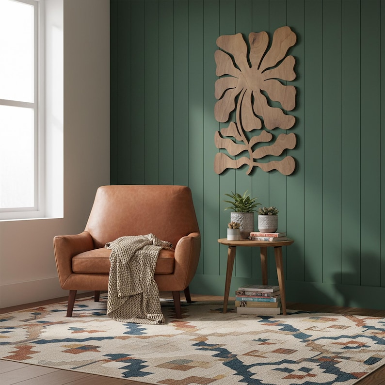 Peut inclure: Int&eacute;rieur de salon avec un fauteuil en cuir marron et une couverture beige. Une petite table d'appoint en bois avec des plantes en pot et un tapis &agrave; motifs. Une grande &oelig;uvre d'art murale florale en bois est accroch&eacute;e au mur vert.