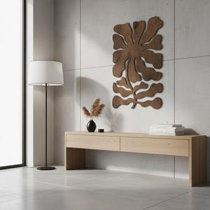Peut inclure: Int&eacute;rieur moderne avec une console en bois clair, un lampadaire noir avec un abat-jour blanc et une &oelig;uvre d'art murale en bois en forme de fleur. Un vase noir avec des plantes s&eacute;ch&eacute;es et une pile de livres sont sur la table.