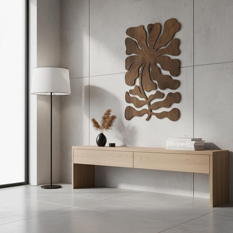 Peut inclure: Int&eacute;rieur moderne avec une console en bois clair, un lampadaire noir avec un abat-jour blanc et une &oelig;uvre d'art murale en bois en forme de fleur. Un vase noir avec des plantes s&eacute;ch&eacute;es et une pile de livres sont sur la table.