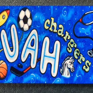 May include: A blue and white background with the word "JAH" in large, white letters with blue outlines. The word "chargers" is written in yellow letters with blue outlines. There are various sports-related images, including a basketball, a soccer ball, a hockey stick, and a rocket ship.