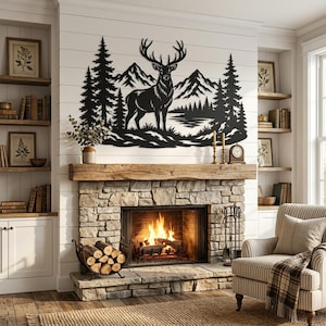 Könnte beinhalten: Ein Wandkunstobjekt aus schwarzem Metall, das die detaillierte Silhouette eines Hirsches in einer Waldlandschaft mit Tannen und Bergen zeigt. Das Design ist an einer weißen Wandtäfelung über einem Steinkamin mit brennendem Feuer angebracht.