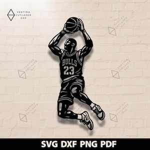 May include: Black and white silhouette of a basketball player in mid-air, holding a basketball above his head. The player is wearing a Bulls jersey with the number 23. The image includes the text "SVG DXF PNG PDF".