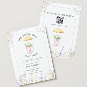 以下が含まれることがあります： 花柄の装飾が施されたベビーシャワーの招待状2枚。 黄色の傘、ピンクの長靴、テキスト「April Showers Bring May Flowers」がデザインされています。 1枚のカードにはQRコードと「Scan here to view registry」が含まれています。