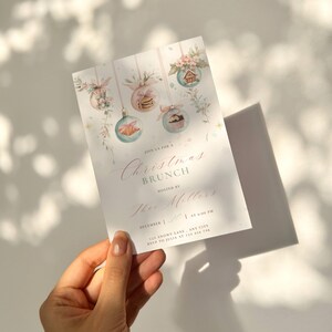 K&ouml;nnte beinhalten: Eine Einladung zum Weihnachtsbrunch mit Aquarellillustrationen von Kugeln, Blumen und Geb&auml;ck. Der Einladungstext lautet "Christmas Brunch" und "Thee Millers". Datum und Uhrzeit sind ebenfalls angegeben.