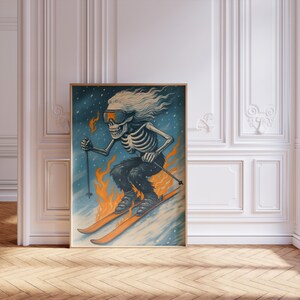 May include: A framed art print depicting a skeleton skiing on a snowy slope. The skeleton wears goggles and has long, flowing hair. Flames are at the bottom, with orange skis and a blue and white background. The artwork is in a wooden frame.