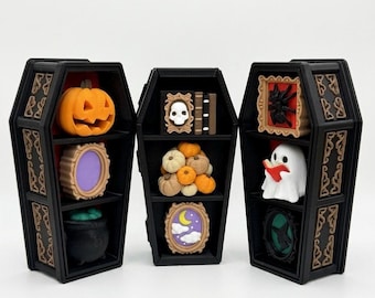 May include: Three black coffin-shaped display cases with red interiors, each featuring shelves holding ten small decorative buttons. The buttons include shapes of a pumpkin, skull, spider, ghost, cauldron, and framed scenes. Text reads: 1 Coffin+10 Buttons.