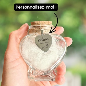 Peut inclure: Un bocal en verre en forme de cœur avec un bouchon en liège, rempli d'une matière blanche. Un pendentif argenté en forme de cœur gravé du nom "Ethan" et des années "2009-2024" est suspendu au bocal. Le texte "Personnalisez-moi !" est dans un encadré noir.