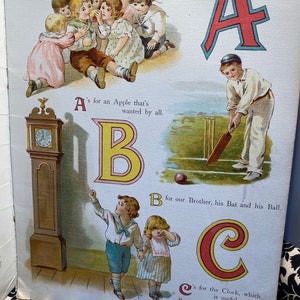 May include: An illustrated alphabet book with colorful letters and images. The letter A is red with a blue outline and shows a boy playing cricket. The letter B is yellow with a red outline and shows a boy and girl standing next to a clock. The letter C is red with a yellow outline and shows a clock.