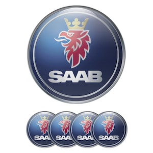 Könnte beinhalten: Ein Satz Saab-Autoaufkleber. Das Hauptemblem ist ein blauer Kreis mit silbernem Rand, der einen roten Greif mit goldener Krone und das Wort "SAAB" in Silber zeigt. Darunter befinden sich vier kleinere Aufkleber.