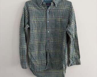 May include: A long-sleeve button-down shirt featuring a plaid pattern in shades of light blue, dark blue, white, and olive green. The shirt has a collared neckline, a front button placket with light blue buttons, and a textured fabric construction.