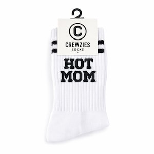 May include: White crew socks with black stripes and the text "HOT MOM" in bold, black letters. The socks have a ribbed texture and a tag that reads "CREWZIES SOCKS" with a "C" logo.