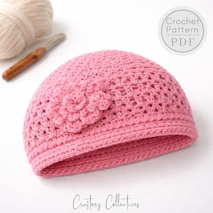 Könnte beinhalten: Ein rosa gehäkelter Hut mit floralem Design. Der Hut ist handgefertigt und hat ein strukturiertes Stichmuster. Das Bild zeigt auch einen Wollknäuel, eine Häkelnadel und den Text "Crochet Pattern PDF" und "Craftory Collectives".