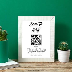 May include: A framed sign with the text "Scan To Pay" and a QR code for Venmo. The sign also includes the text "Thank You for your purchase" and "YOUR BUSINESS NAME". The frame is white, and the background is green.