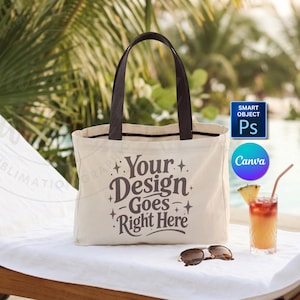 May include: A cream-colored tote bag with dark brown handles and the text "Your Design Goes Right Here" in a decorative font. The bag sits on a white towel next to sunglasses and a tropical drink with a pineapple garnish.