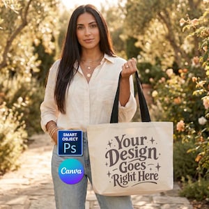 May include: A beige tote bag with black handles. The bag features the text "Your Design Goes Right Here" in a decorative font. The image also includes a woman in a light-colored shirt and jeans, standing outdoors.