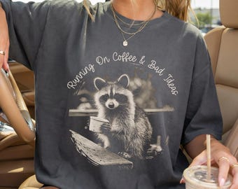 PNG de "Correr con café y malas ideas", gráfico divertido de mapache con café, diseño de sublimación de animales del bosque vintage