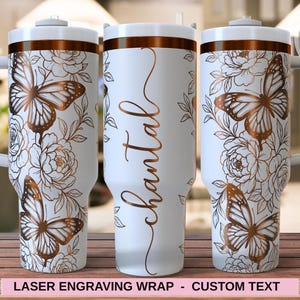 Op de afbeelding: Witte beker met een koperen vlinder- en bloemenontwerp. De beker heeft een handvat en een deksel. Het woord "Chantal" is verticaal in koperkleurig schrift geschreven. De onderkant van de beker heeft de tekst "LASER ENGRAVING WRAP - CUSTOM TEXT".