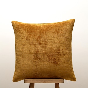 Peut inclure: Un coussin carré décoratif de couleur jaune doré. Le coussin présente une surface texturée et est posé sur un tabouret en bois. La couleur et la texture suggèrent une sensation de douceur et de confort, idéale pour la décoration intérieure. Mesure environ 40 cm x 40 cm.