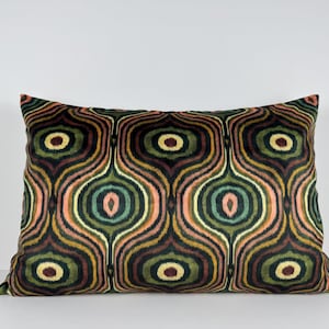 May include: Rectangular cushion featuring a repeating pattern of oval shapes in green, brown, orange, and pink. The cushion has a soft, velvety texture and is designed for home decor.