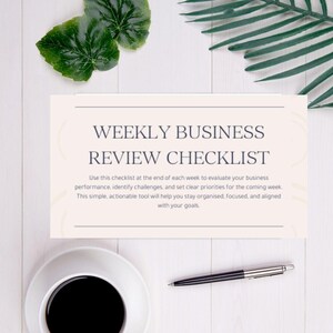 Puede incluir: Una vista cenital de una lista de verificación de revisión comercial semanal de color crema con texto. Una taza de café negro, un bolígrafo y hojas verdes están dispuestos sobre una superficie de madera blanca.