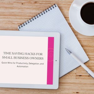 Op de afbeelding: Een witte tablet met de tekst "TIME SAVING HACKS FOR SMALL BUSINESS OWNERS" met een roze streep, een spiraalvormig ontwerp, een koffiekopje, een notitieblok en een pen op een houten oppervlak.