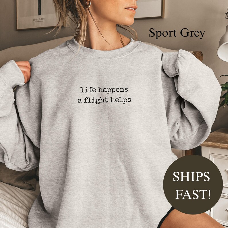 Light grey sweatshirt with text "life happens a flight helps" and "SHIPS FAST!".