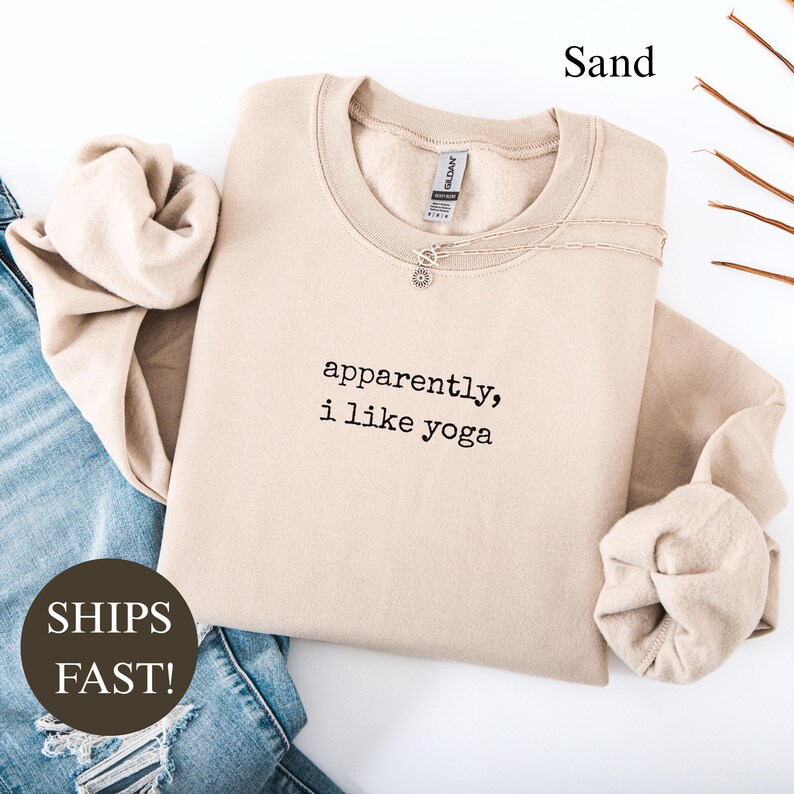 Sand colored crewneck sweatshirt with "apparently, i like yoga" printed on it.