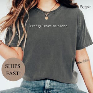 Dark grey t-shirt with "kindly leave me alone" printed in white.
