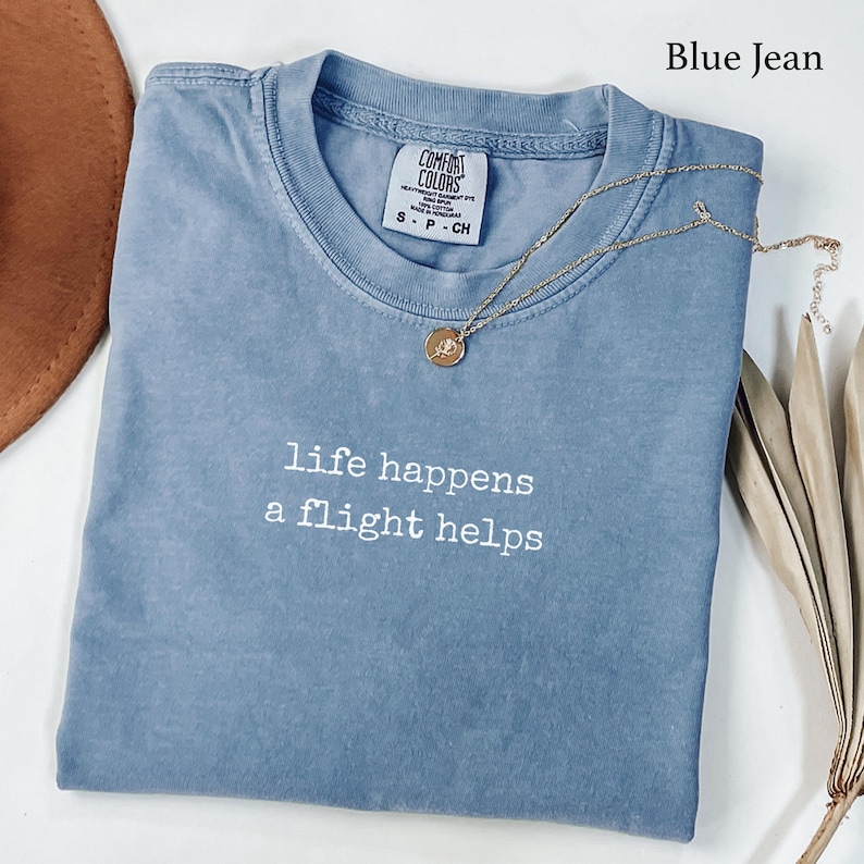 Blue short-sleeve shirt with "life happens a flight helps" text.