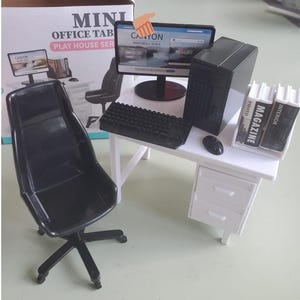 May include: Miniature office desk set with a black computer, keyboard, mouse, and magazines. The desk is white with a black chair. The computer screen displays "CANYON WATERFALL RIVER". The set is part of a "PLAY HOUSE SER" series.