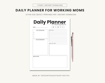 May include: A white daily planner for working moms with the text "Daily Planner for Working Moms". The planner is letter size (8x10 inches) and includes sections for priorities, reminders, and tasks. A pink pen rests beside the planner.