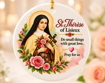 May include: A round white ceramic ornament featuring an illustration of Saint Thérèse of Lisieux holding a crucifix and roses. The text reads St. Thérèse of Lisieux, Do small things with great love, and Pray for us, accented by a small pink heart.