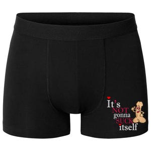 Puede incluir: Bóxer negro con un gráfico humorístico. El bóxer presenta el texto "It's NOT gonna SUCK itself" en rojo y blanco, junto con una ilustración de dibujos animados de un pene con gafas de sol.
