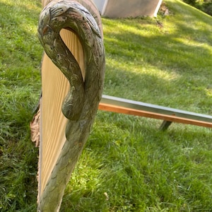 May include: An antique bed frame with a carved, ornate headboard and footboard. The headboard features a decorative, curved design with a light green and gold finish. The bed frame is set on a grassy lawn.