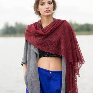 Peut inclure: Une femme portant un cardigan gris, un pantalon bleu et un ch&acirc;le en dentelle bordeaux. Le ch&acirc;le est drap&eacute; autour de son cou et de ses &eacute;paules.